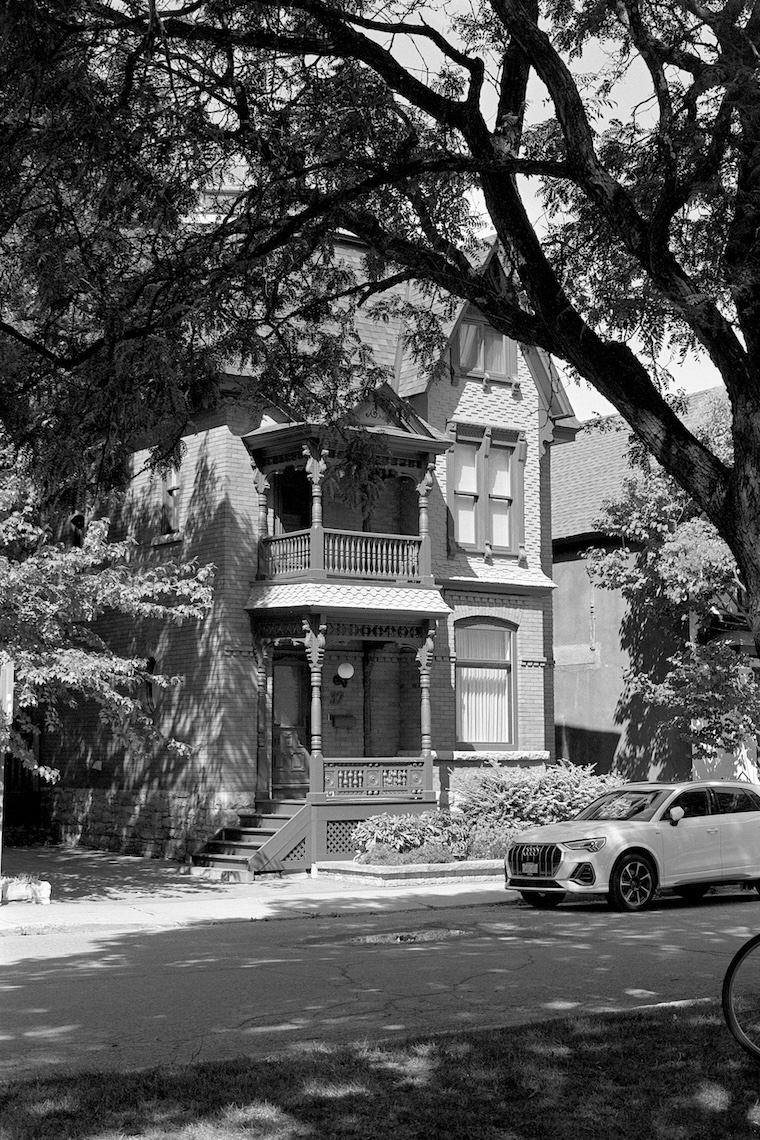 Photo of a two-storey nineteenth-century home, as seen through a small parkette. Click for full size.